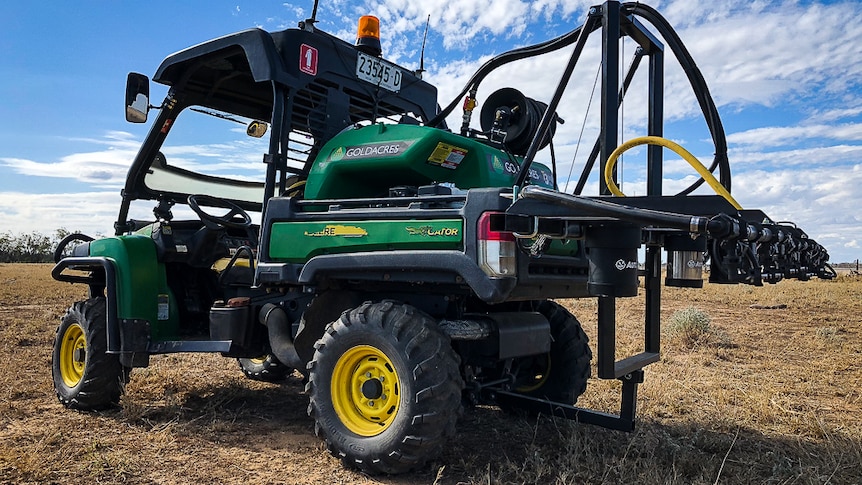 A spraying machine with sensors below it sitting on the back of a ATV