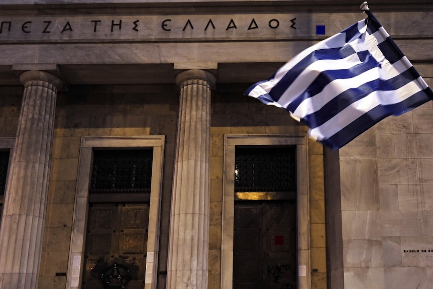 A Greek flag flies outside the headquarters of bank of Greece in central Athens.