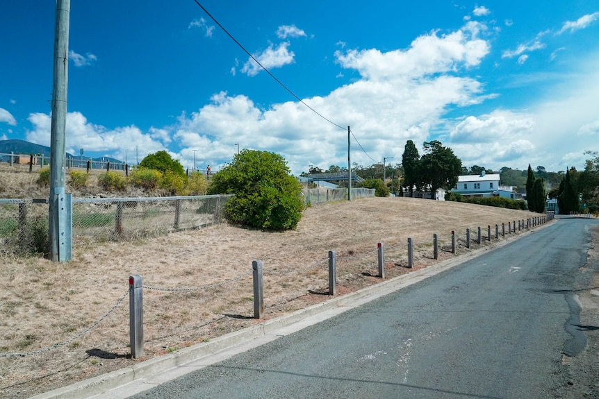 The site of the proposed tram museum at Regatta. A road runs past empty land, and a building is seen in the distance.