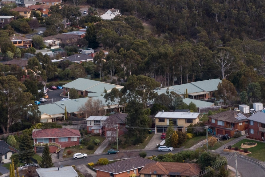 An aerial view of suburban homes with a four-pronged building overhead