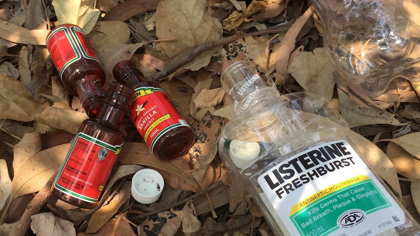 Empty vanilla essence bottles, a mouth wash and a soft drink bottle left in the dirt