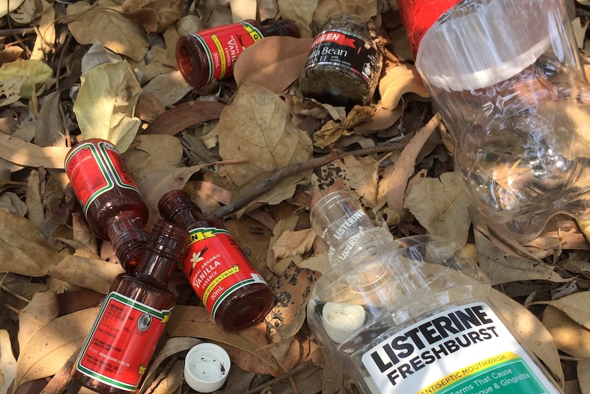 Empty vanilla essence bottles, a mouth wash and a soft drink bottle left in the dirt