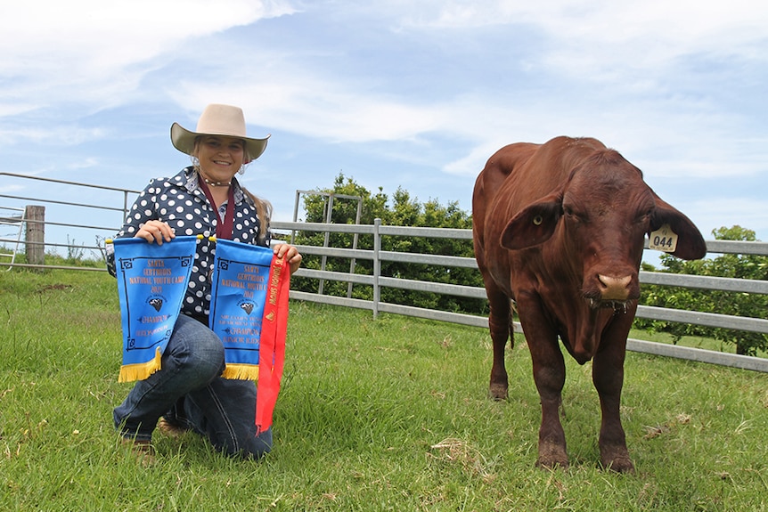Georgia Perkins displays her medallion and ribbons next to her winning heifer.
