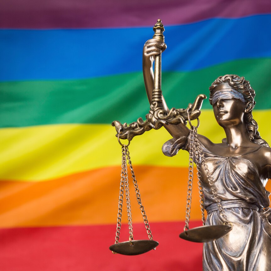 The blindfolded goddess of justice Themis or Justitia against the rainbow flag of LGBTQIA+ community