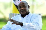Uganda's President Yoweri Museveni in a chair in front of a green background. 