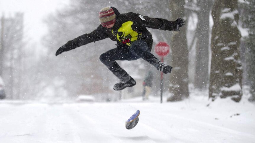 A man snowboards down a suburban street in Pittsburgh