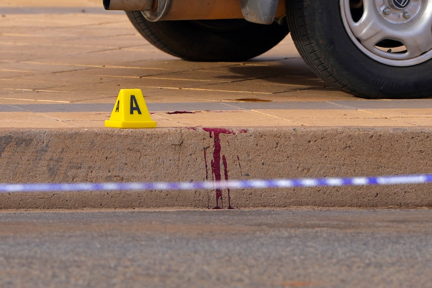A yellow evidence marker next to blood on a footpath at wolfram street in Broken Hill. 