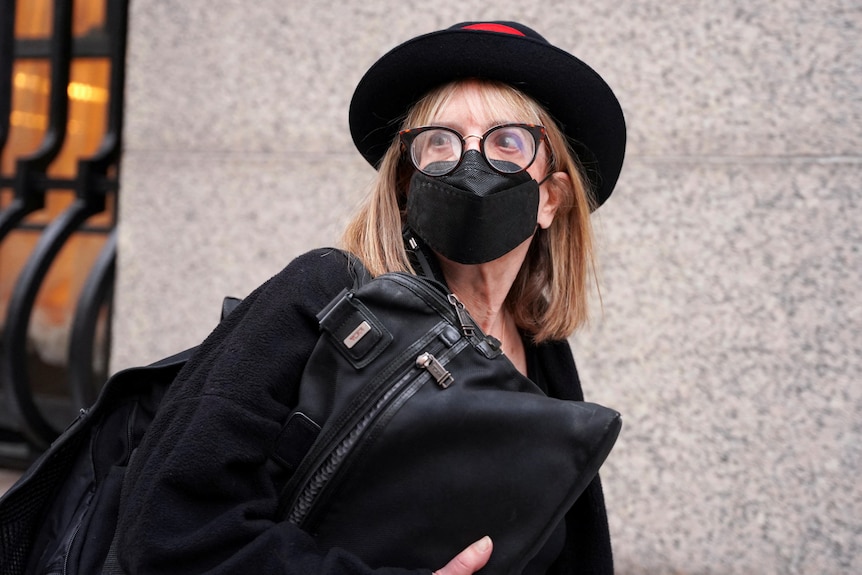 A woman in black in a hat catching a bag and wearing a mask