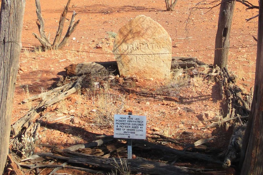 Bush grave marked by sticks and a large rock with rough fence posts.