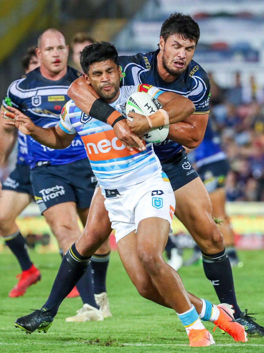 Tyrone Peachey holds the ball with his left arm as he is tackled from behind by Jordan Peachey.