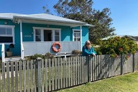 A woman stands in front of a blue house