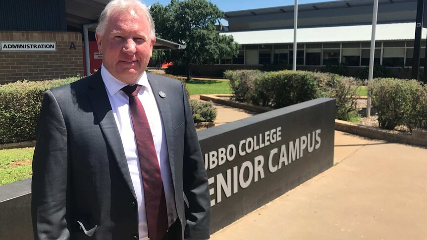 The Principal of Dubbo Senior Secondary College stands at the school entrance.