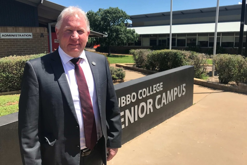 The Principal of Dubbo Senior Secondary College stands at the school entrance.