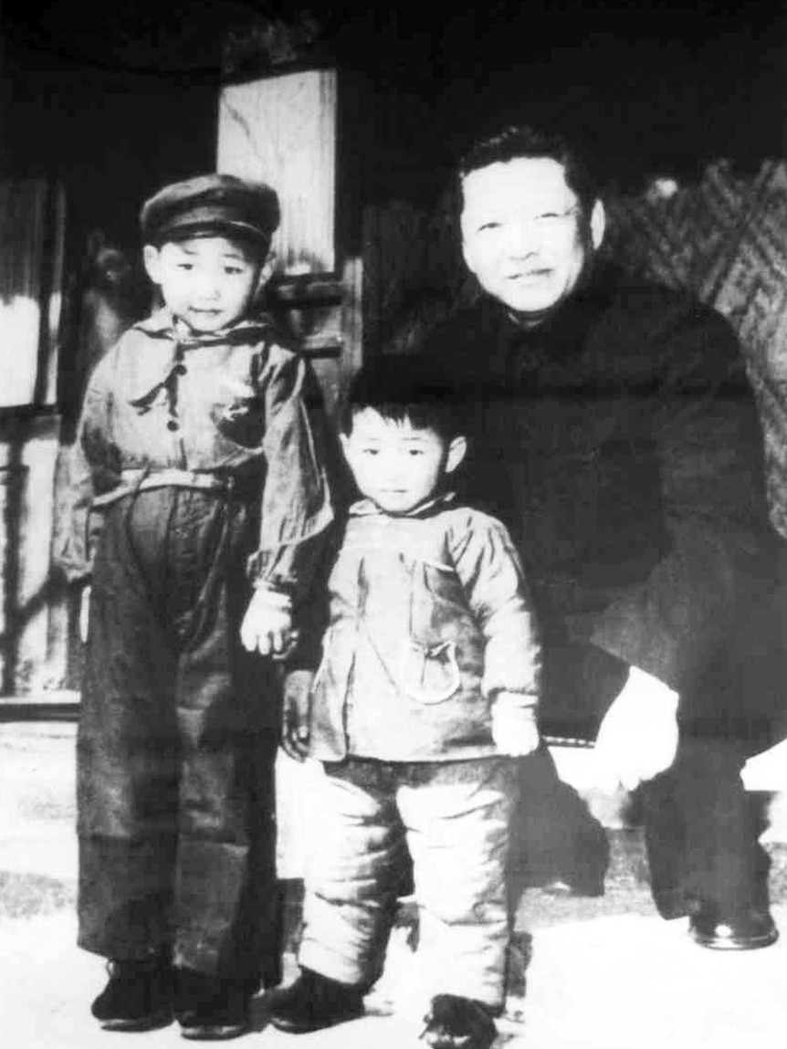 A 1950s black and white photo of a Chinese man with two children