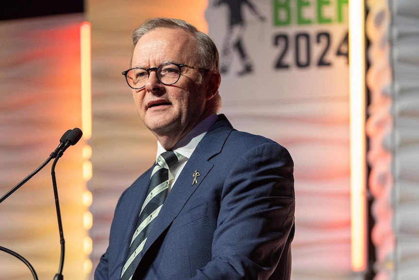 Anthony Albanese speaks into a microphone in front of a sign that says BEEF 2024