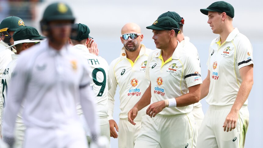 Australia bowler Nathan Lyon stands with teammates as they watch South Africa batter Kyle Verreynne walk off.