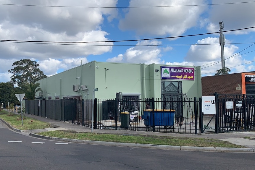 The outside view of the Ahulalbait mosque in Victoria, which appears as a simple grey building with a black fence.