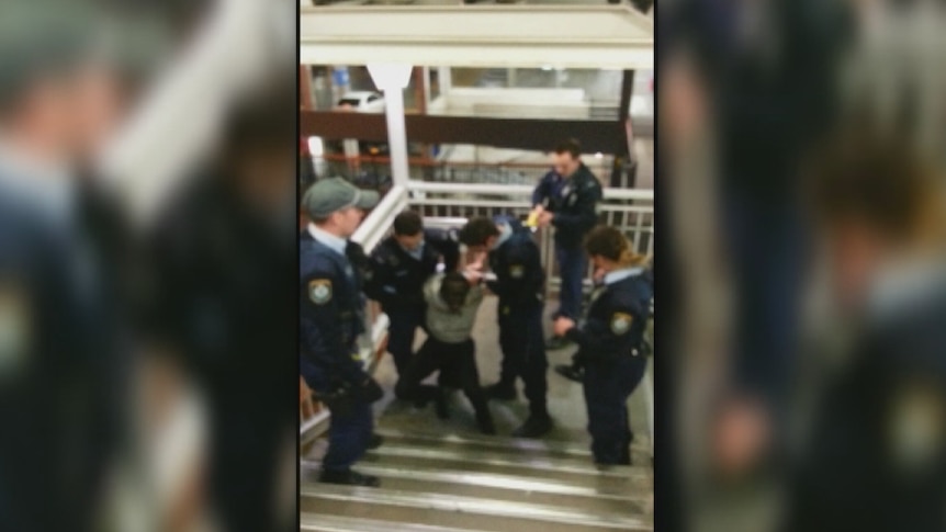 Einpwi Amom is restrained by police