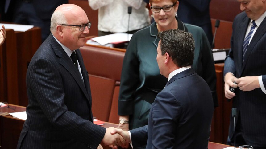 George Brandis and Dean Smith shake hands after the same-sex marriage bill passes Senate.