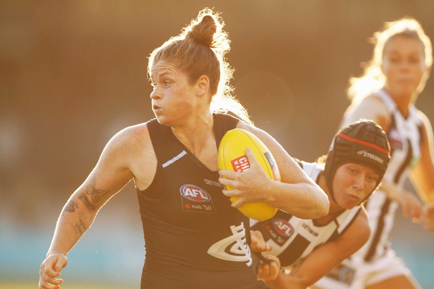 Brianna Davey's jersey is stretched as she is tackled from behind. She is looking to break away while carrying the ball.