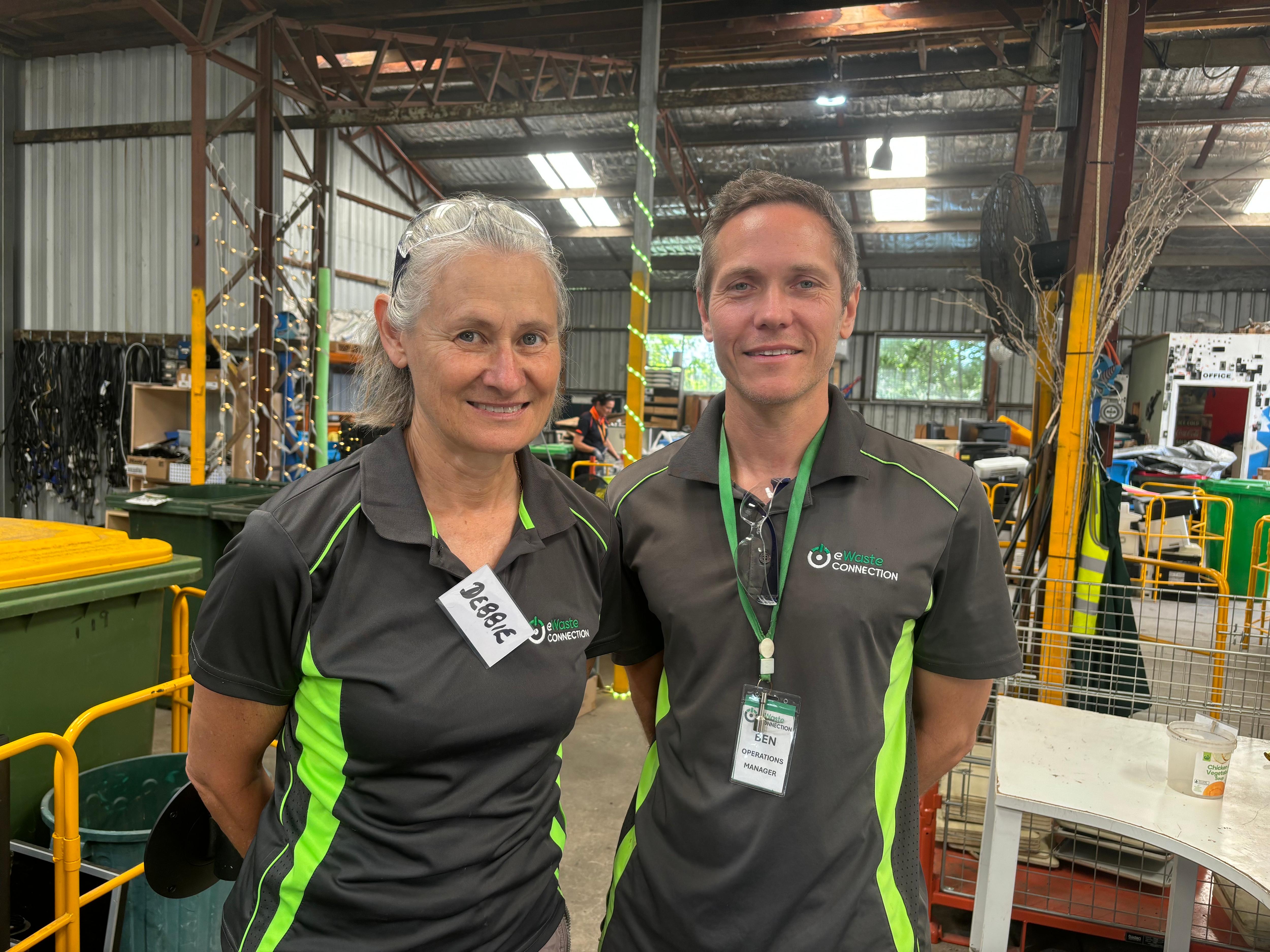 Una mujer y un hombre uniformados en un taller. 