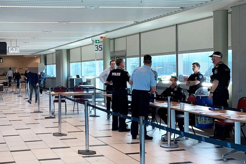 Airport staff and Queensland police officers at a security checkpoint at Brisbane airport to screen passengers.
