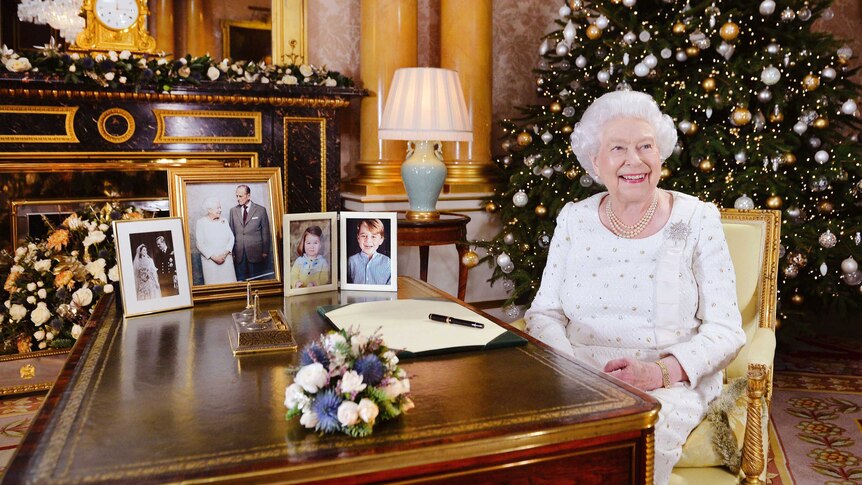 Queen Elizabeth sits at a desk in Buckingham Palace.