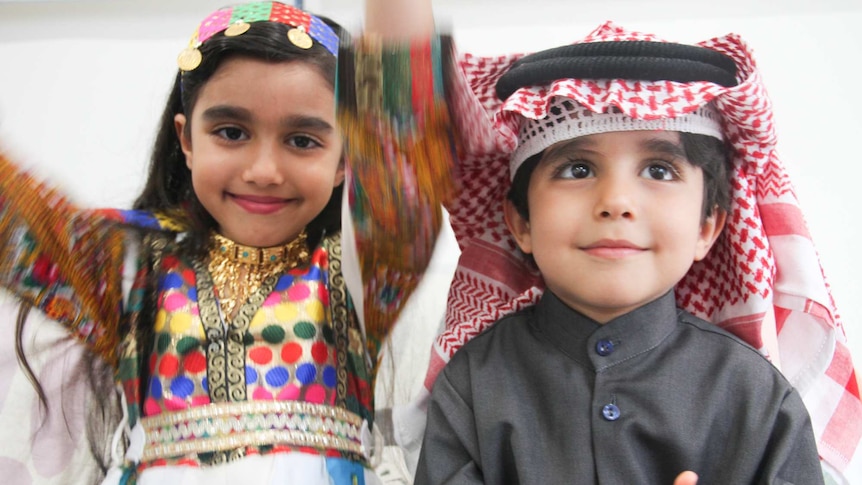 Two young children wearing the colourful traditional dress of Syria