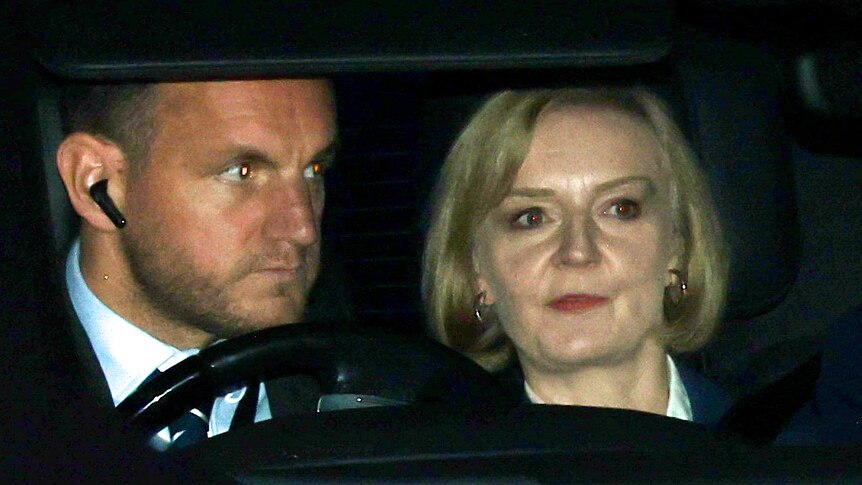 a long lens image of liz truss in the back of her car, security in the front seat
