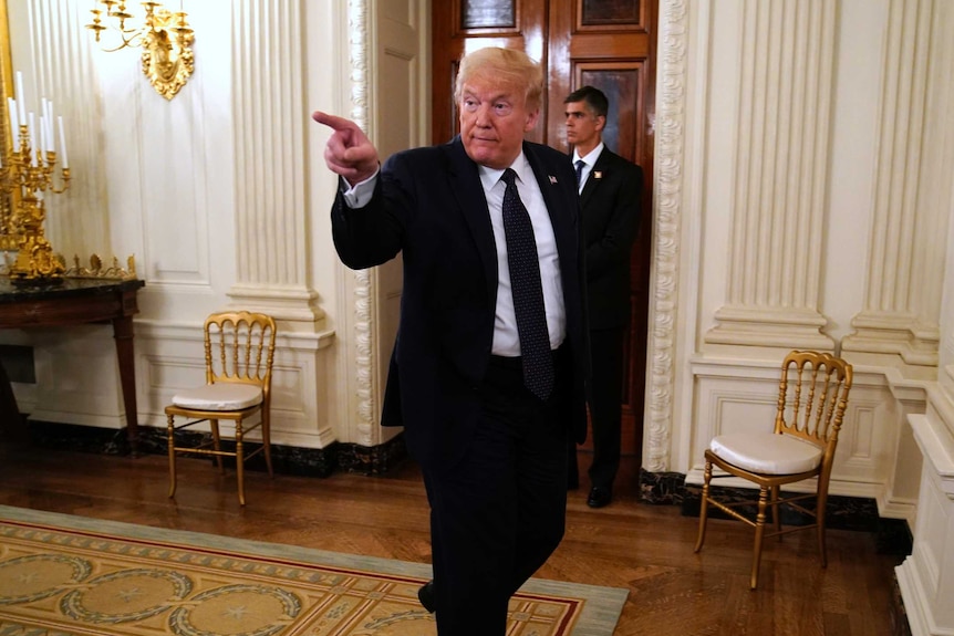 President Donald Trump points as he walks out of a dining room at the White House