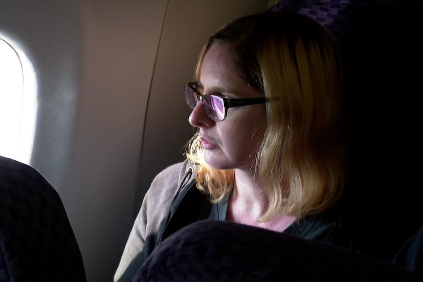 A woman looks out of the window of a plane.