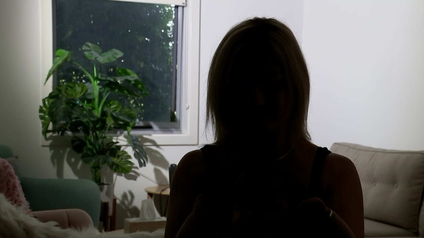 The silhouette of a woman against a white wall.