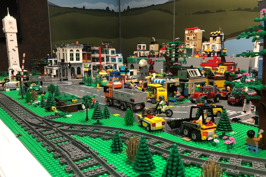 A model city made of Lego, complete with train tracks, cars and trucks, buildings and roads.