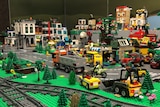 A model city made of Lego, complete with train tracks, cars and trucks, buildings and roads.