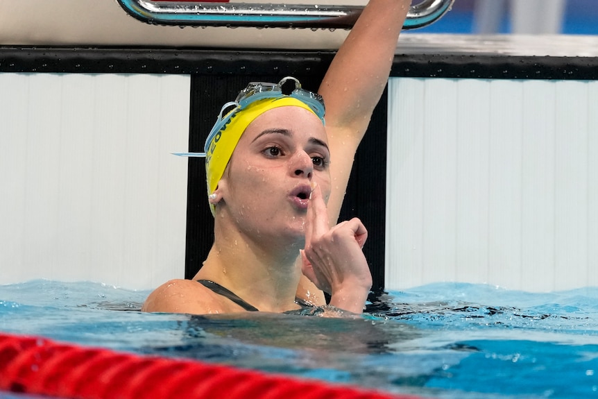 Natación soplando un gesto de pistola después de ganar una medalla olímpica 