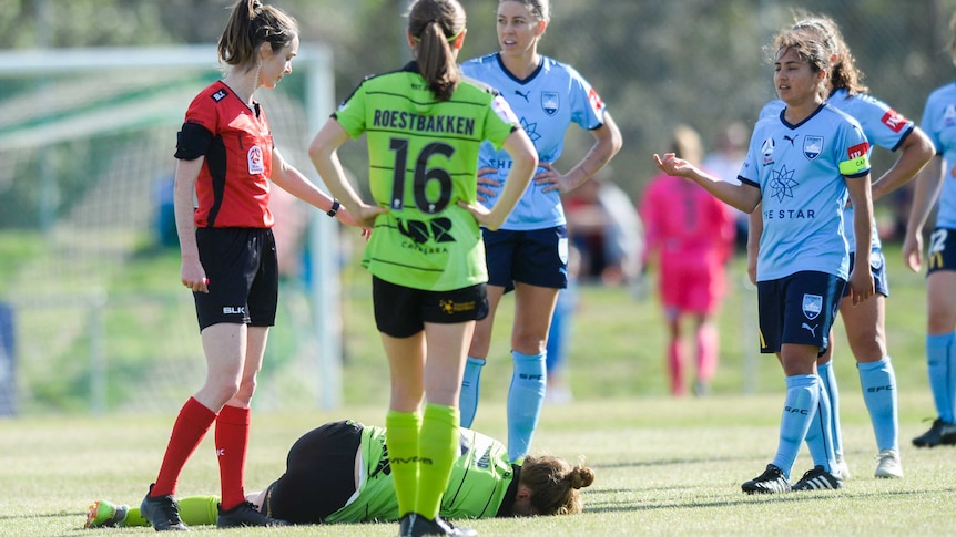 A soccer player in on the ground after being injured.