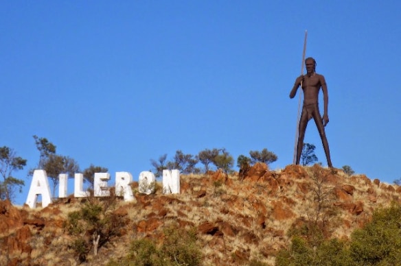 A statue of an Aboriginal hunter on a hill.