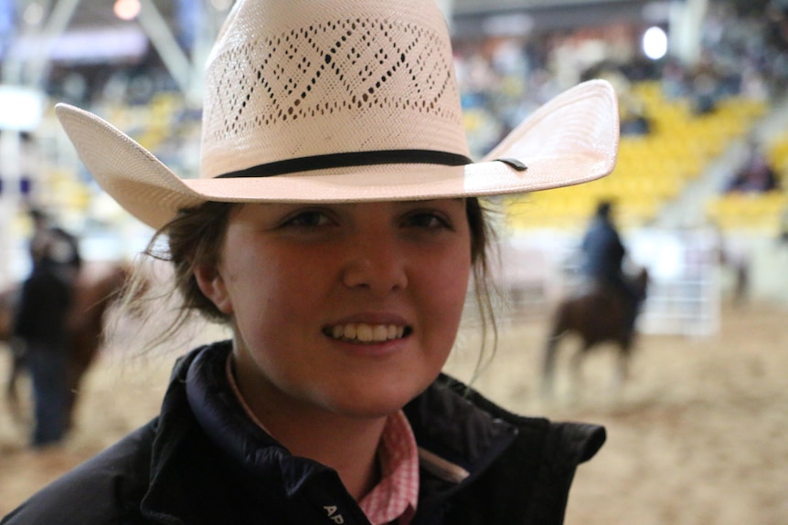 A teenage girl in a white hat looks at the camera.