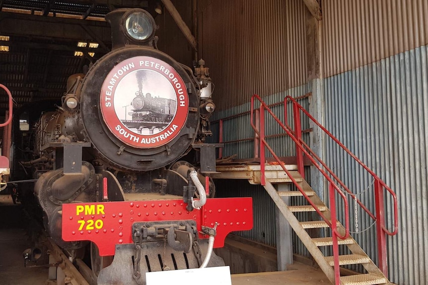 A large black locomotive sits under a corrugated roof.