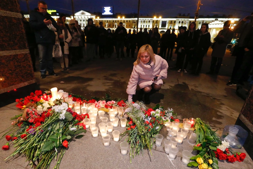 A woman places flowers outside Tekhnologicheskiy Institut metro station in St. Petersburg, Russia, April 3, 2017.