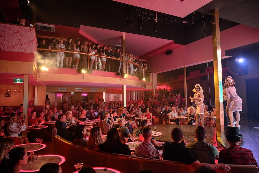 The interior of a nightclub, with a full crowd watching a performance.