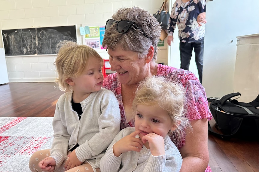 A nanna looks down at her two-year-old twin granddaughters.