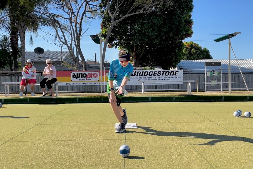 Young lawn bowls player released a ball down a black line on the greens