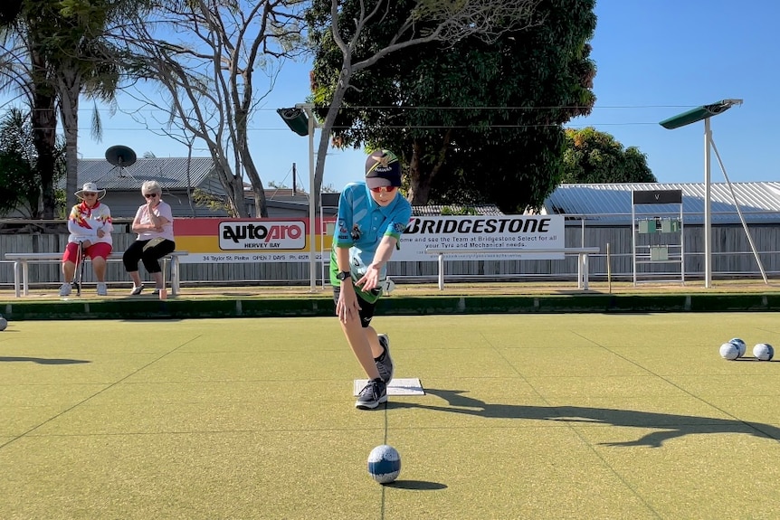 Young lawn bowls player released a ball down a black line on the greens