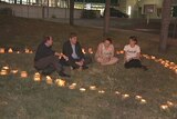 Four people sit in a heart-shaped collection of candles