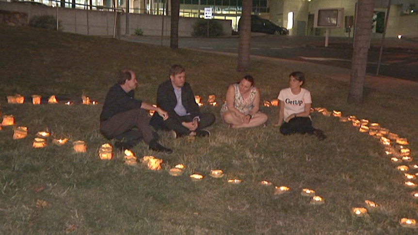 Four people sit in a heart-shaped collection of candles