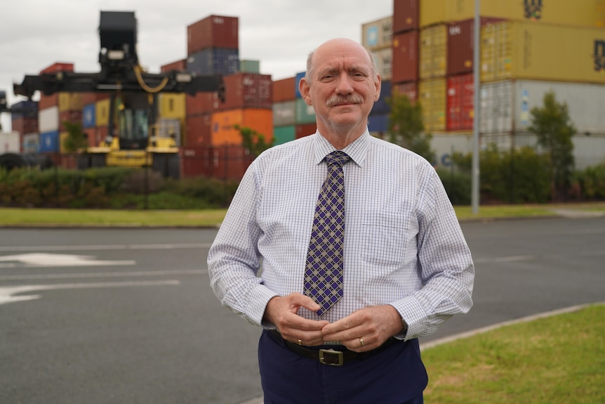 A man standing in front of shipping containers