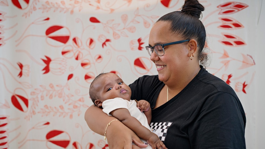 An Aboriginal woman smiles at her baby