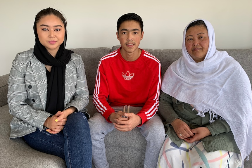 A man and two women sit on the couch.