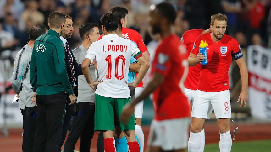 A team manager talks to a referee after an international game is halted because of racist abuse.